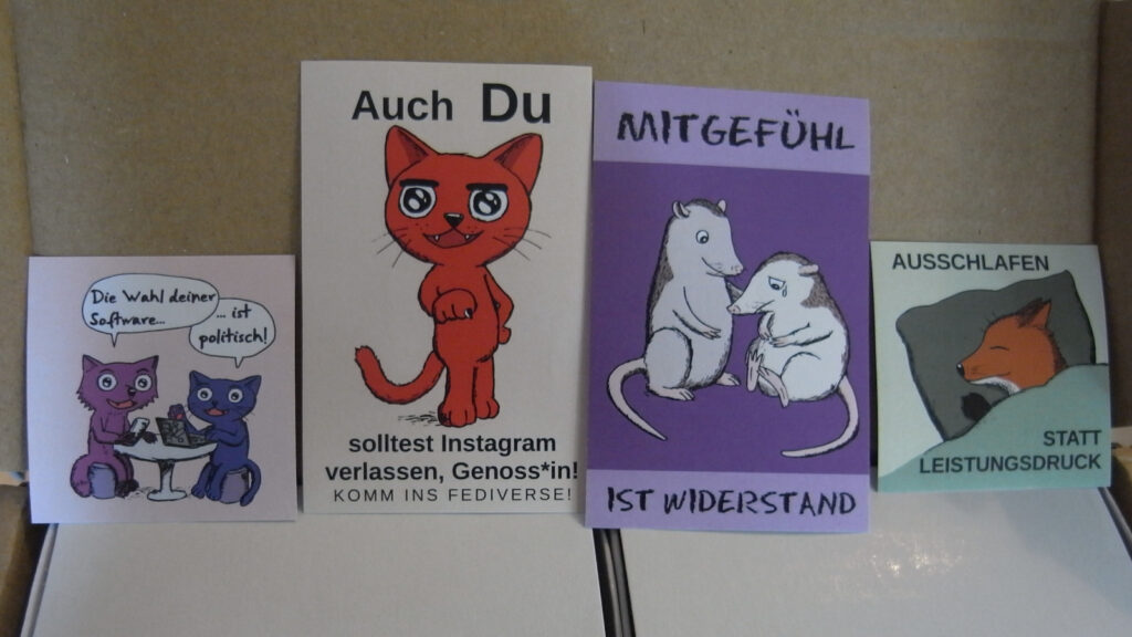Vier Aufkleber in einer Schachtel:
Motiv 1
Fuchs und Katze sitzen an einem Tisch, gucken einen an. Fuchs hat ein Smartphone, Katze einen Laptop.
Fuchs: Die Wahl deiner Software...
Katze: ... ist politisch!
Bezeichnung: Wahl-Software-politisch_Fuchs-Katze

Motiv 2
Eine Katze die herausfordernd auf einen zeigt, in Anspielung auf das Motiv mit dem Rote Armee Typen, der sagt "Auch du hältst die Küche sauebr, Genosse", die Katze sagt aber: Auch Du solltest Instagram verlassen, Genoss*in! Komm ins Fediverse!
Bezeichnung: Auch-Du-Instagram-Fediverse_Katze

Motiv 3
Zwei Opossums, das eine sitzt, sieht unglücklich aus und weint, das andere tröstet das erste. Text: Mitgefühl ist Widerstand.
Bezeichnung: Mitgefuehl-Widerstand_Opossum

Motiv 4
Ein Fuchs der im Bett liegt und zufrieden schläft. Text: Ausschlafen statt Leistungsdruck
Bezeichnung: Ausschlafen-Leistungsdruck_Fuchs